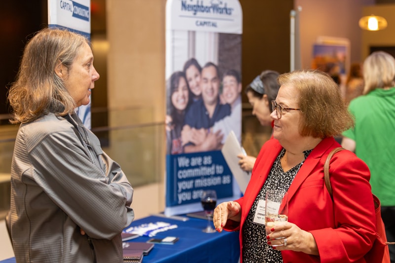 NeighorWorks Capital staff member explaining our solutions to someone at our booth at a conference